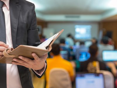 Businessman writing the note book on the Abstract blurred photo of conference hall or seminar room with attendee background