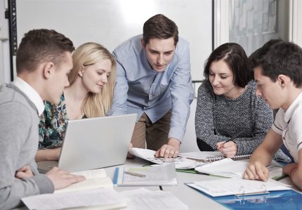 Teacher Working In Classroom With Students